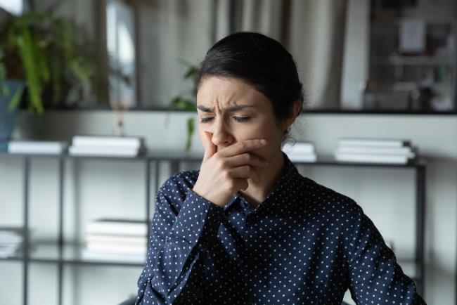 אישה סובלת משייעול וקוצר נשימה המהווים אחת מקבוצות התסמינים של קוביד 19 לפי מחקר חדש